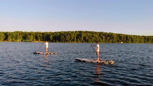 Two Friends Smoothly Sail Away From the Shore of the Lake and Row with Oars