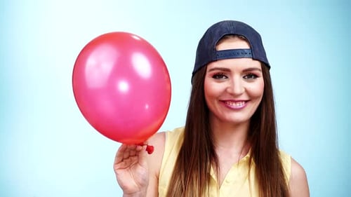 Smiling Woman Holding Pink Balloon in Studio