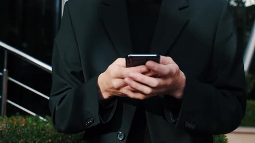 Junger kaukasischer Mann hält Smartphone-Gerät SMS-Nachricht außerhalb des Geschäftsbüros, Verwenden