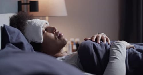Woman Resting in Bed with Compress