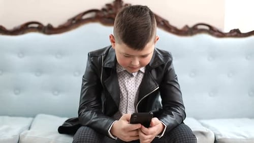 Stylish Boy With Phone Sits on Couch