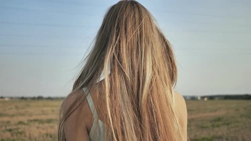 A Young Blonde Girl Stands with Her Back Demonstrating Her Long Hair
