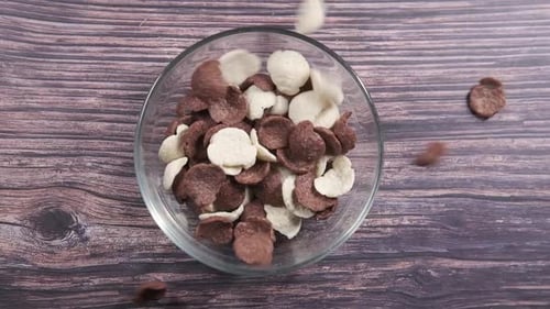 Top View of Falling Chocolate Corn Flakes in a Bowl on Table