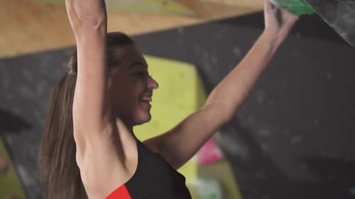 Athletic Woman Climbing Indoor Rock Wall