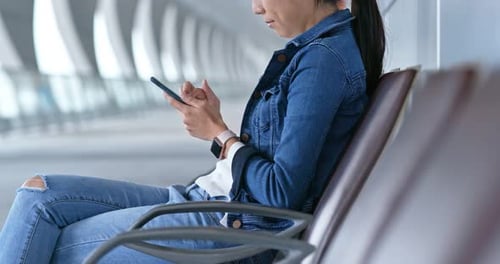 Woman Using Smartphone Sitting on Bench in Urban Area