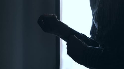 Man Adjusting Shirt Cuff in Dark Silhouette
