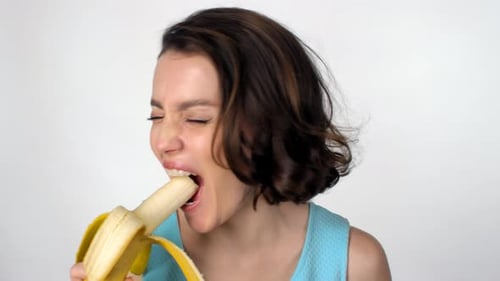 Woman Eating Banana and Smiling Cheerfully at Camera
