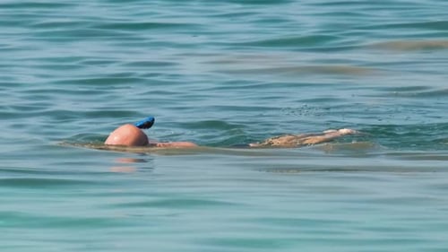 Unrecognizable Man Swimming with Snorkeling Breathing Mask Under Sea Water Surface