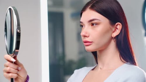 Woman Looks in Mirror During Beauty Treatment
