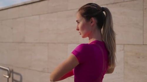 Young Blonde Woman is Doing Physical Exercise Outdoors in City in Summer Morning