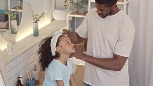 Father Combing Daughter's Curly Hair in Bathroom