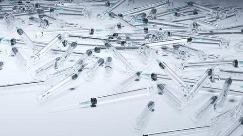 Looping animation with a pile of used clear plastic disposable syringes. 4K