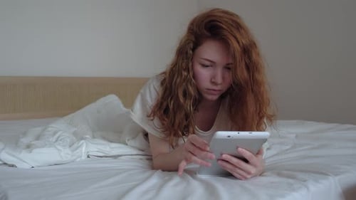 Woman Relaxes in Bed Using Digital Tablet