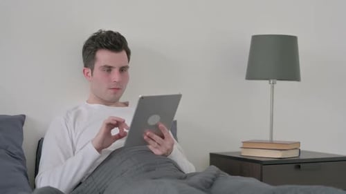 Man in Bed Reacts to Tablet Content
