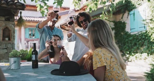 A group of young friends laughing and toasting in a garden of a mediterranean wine cellar