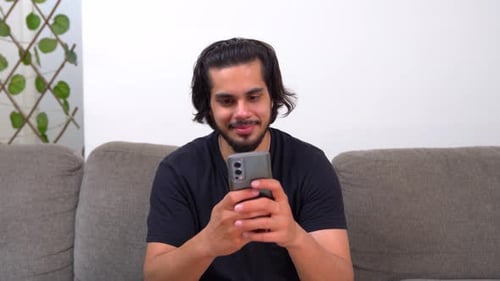 Young Man Using Smartphone While Relaxing on Couch