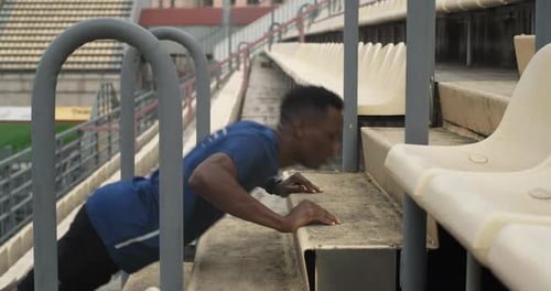 Young Man Doing Push-ups on Stadium Stairs