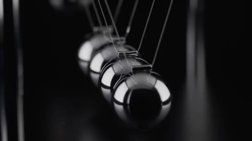 The balls of a Newtons Cradle colliding in slow motion