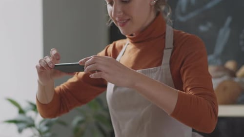 Woman Photographs Vegetables with Smartphone in Bright Kitchen