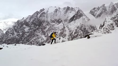 Young Man Yellow Jacket Walking Up Mountain Slope Backpacking Winter Hike Extreme Conditions Swiss