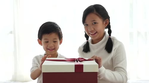 Smiling Children Opening a Gift Together
