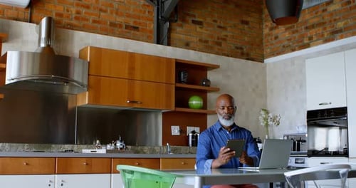 Man Uses Laptop and Tablet in Modern Kitchen
