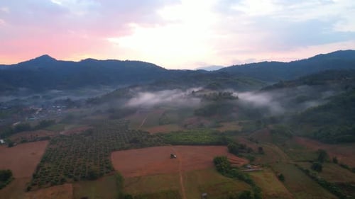 aerial view A drone fly over a rural area with mountains in the background at sunrise.