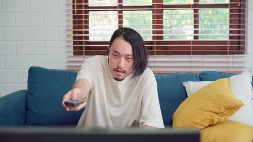 Man on Couch Laughing While Using Remote