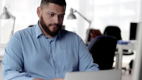 Focused Pensive Office Employee Using Laptop at Workplace