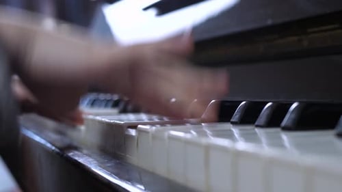 Child Plays Piano Keys in Close Up