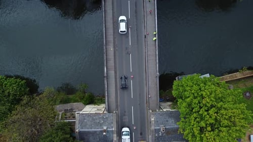 Top down aerial of signal led trafficing in single file across an old victorian road bridgte under r