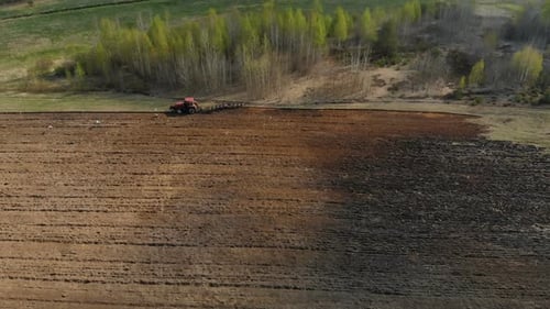 Leistungsstarker Traktor in Rot mit Pflug, Arbeiten, Pflügen, Behandlung von dunklem Boden vor dem Hintergrund