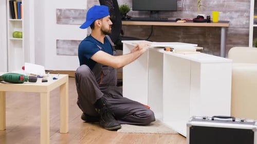 Zoom avant d'un homme en salopette qui assemble une étagère