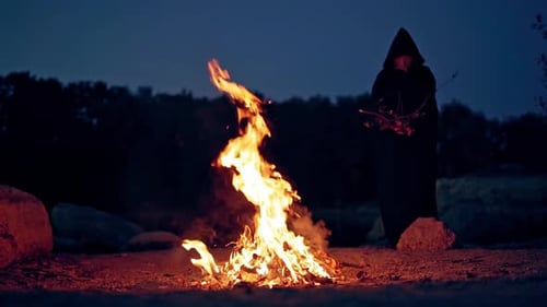 Hooded Figure by a Campfire at Night