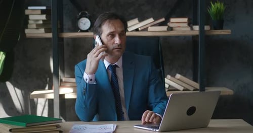 Businessman Working at Desk, Talking on Cell Phone