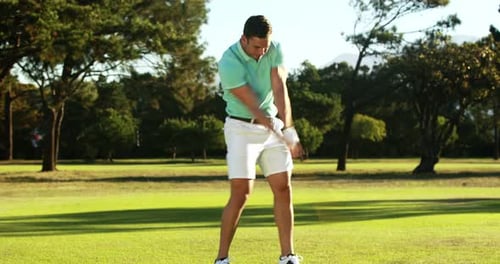 Man Swinging Golf Club on Green Course