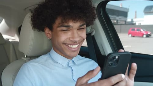 Man Smiling While Using Mobile Phone in Car