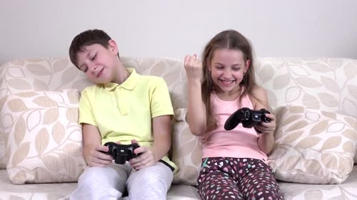 Bruder und Schwester spielen Videospiele auf der Couch liegend