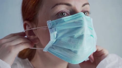 Woman Puts on Blue Disposable Face Mask