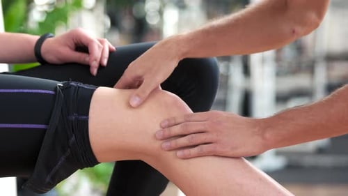 Doctor Examining Woman's Knee with Palpation