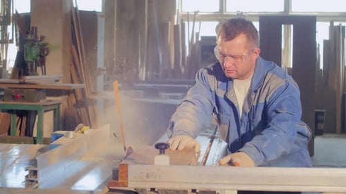 Man Cuts Wood Plank in Workshop with Table Saw