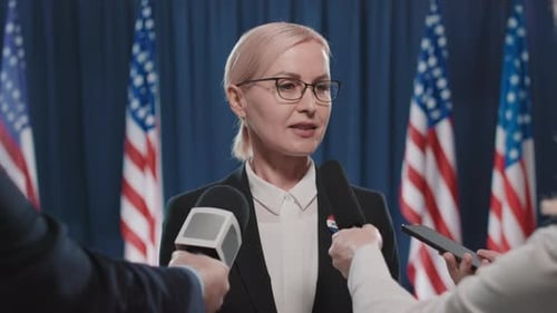 Woman Giving Press Conference with American Flags