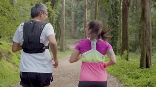 Man and Woman Running on Trail in Forest