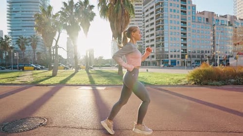 Slim Young Female in Jogging Suit Run By City Street