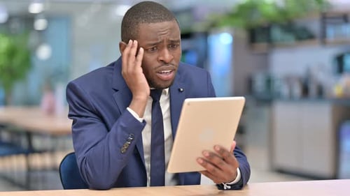 African Businessman Reacting To Loss on Tablet in Office