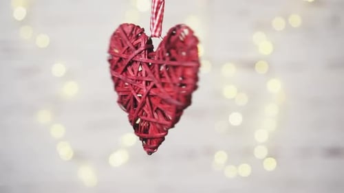 Red Woven Heart Rotating on Ribbon Against Lights