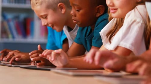 Crianças em idade escolar usando tablet digital na biblioteca
