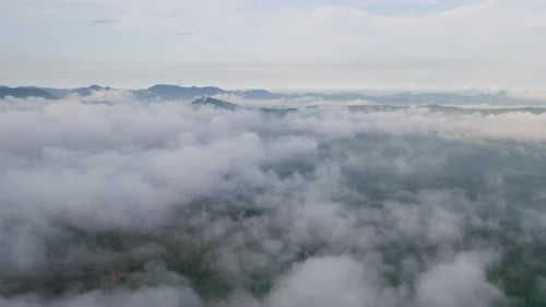 Vista aérea del amanecer sobre la esponjosa niebla marina, nubes brumosas con una colina de montaña