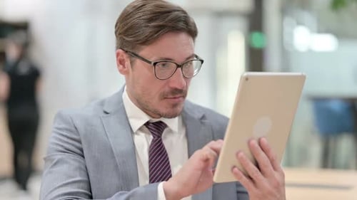 Businessman Receives Good News on Tablet, Celebrates