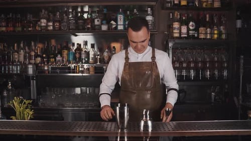 Bartender prepares cocktails behind restaurant bar